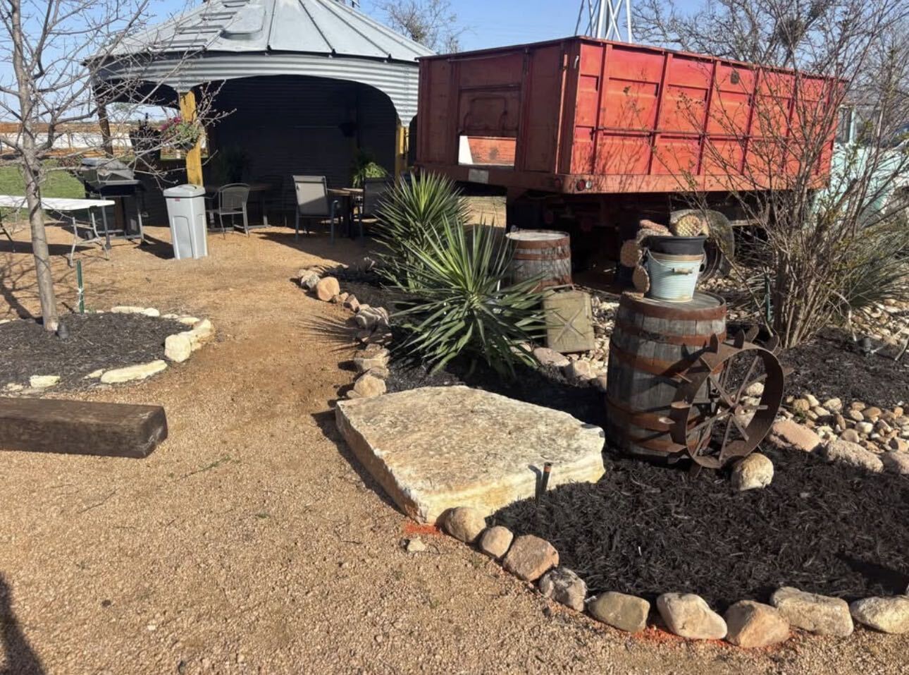 The grain-bin gazebo and grill area beside the vintage red Z-Ranch truck bed, framed by rock gardens and yucca
