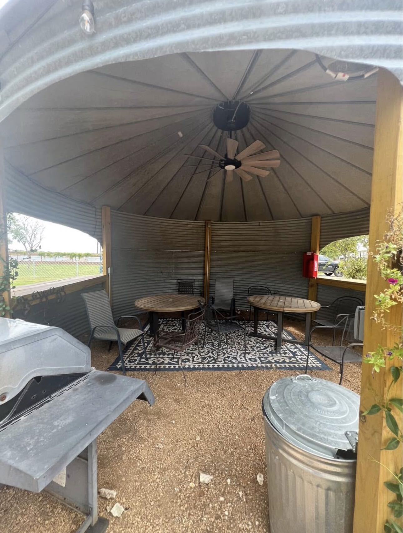 Inside the grain-bin gazebo — round tables, chairs, a ceiling fan and a grill for family gatherings
