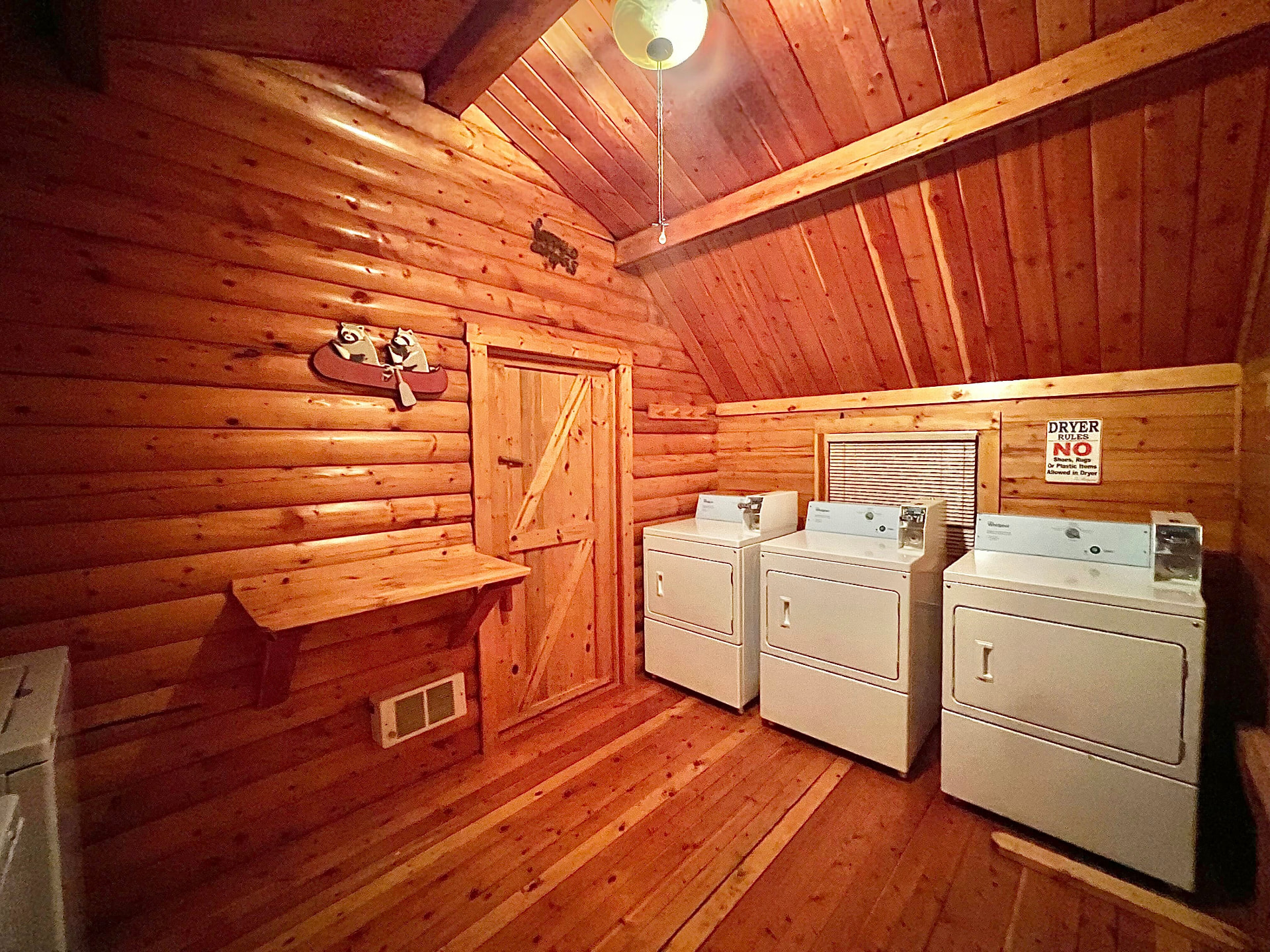 Inside the cedar-lined Z-Ranch laundromat with three coin washers and dryers and a folding shelf