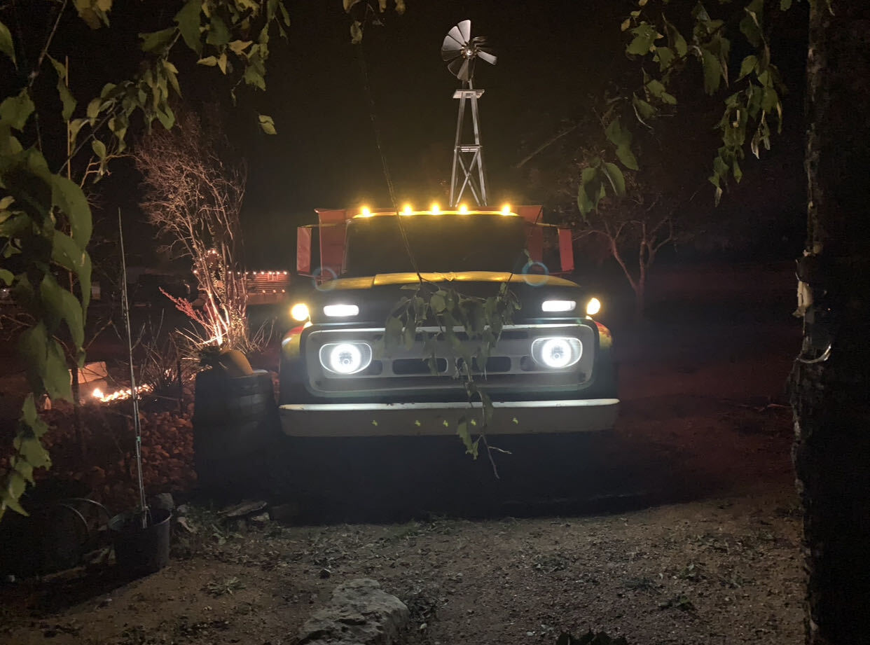 The vintage Z-Ranch truck lit up at night beneath a windmill at the entrance to the park