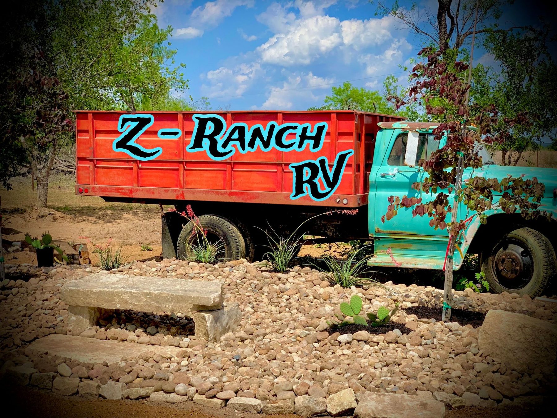 The vintage turquoise and red Z-Ranch RV truck, hand-lettered and planted in a rock garden at the park entrance